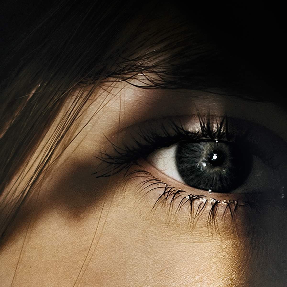 Close up photo of a woman’s eye (from the cover of His Crimes Her Secrets).