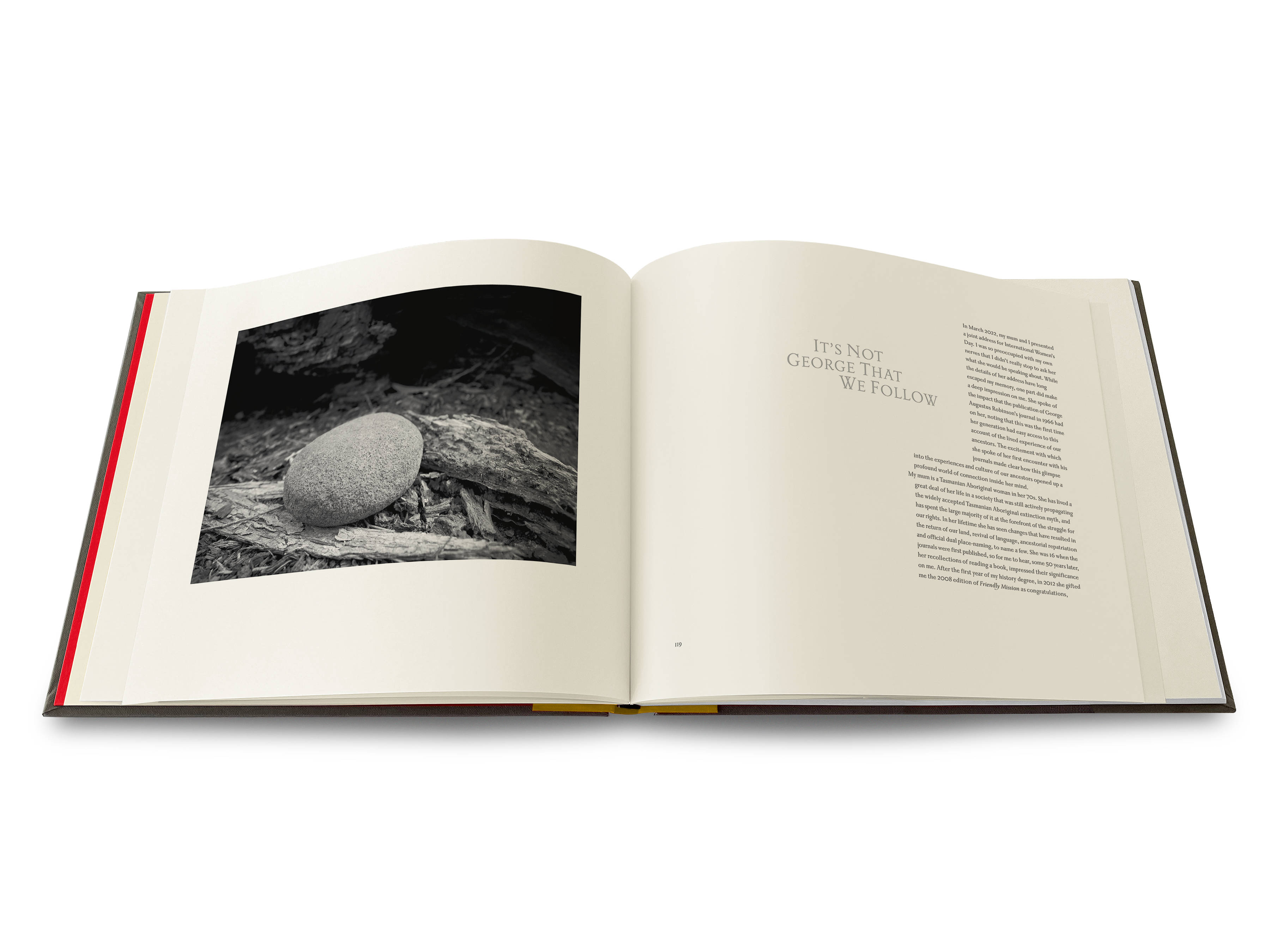 An image of a double-page spread from the Uninnocent Landscapes book with an image of a round river stone on the left and a text page with the words ‘It’s not George that we follow’ on the right.