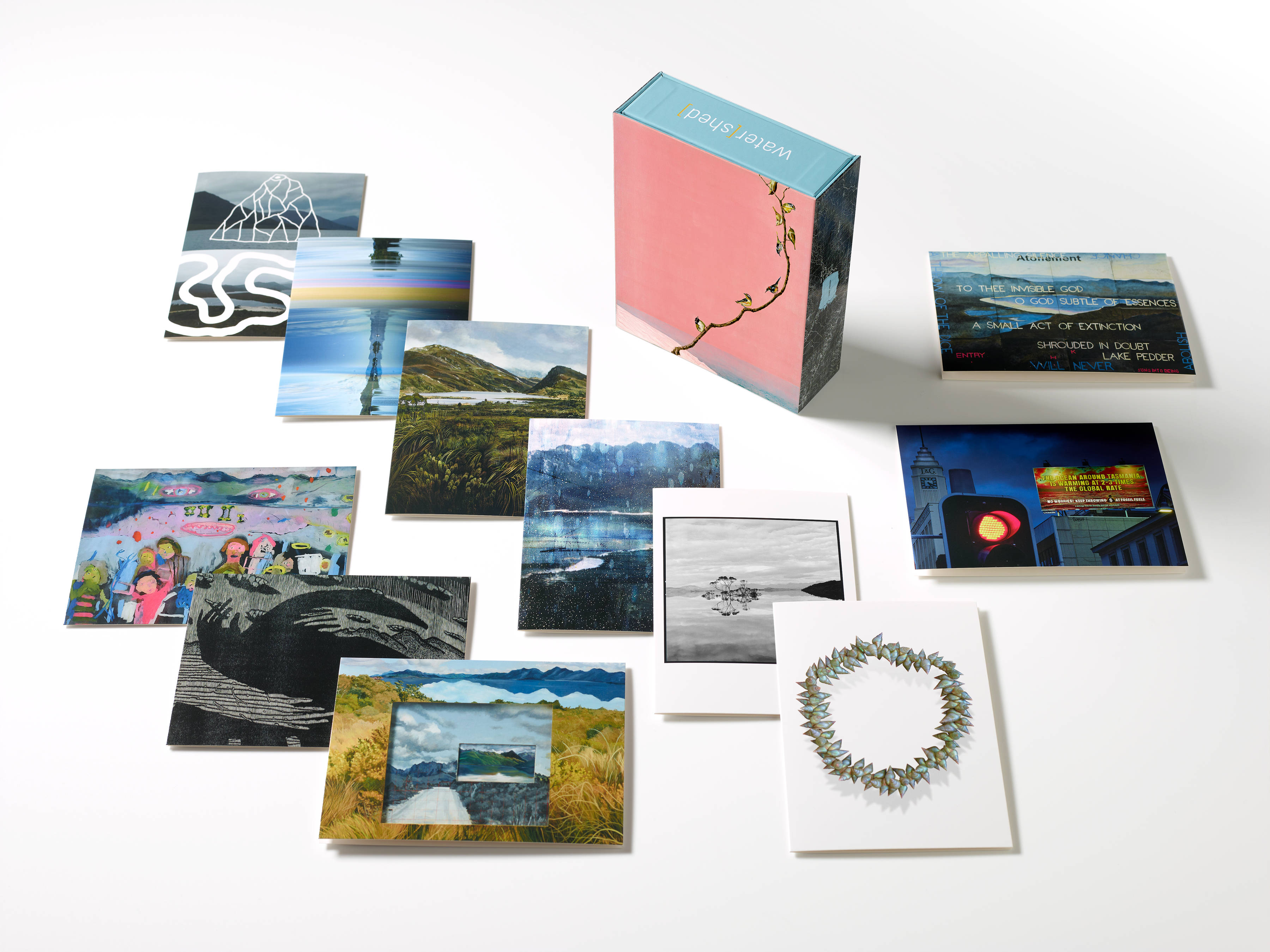 Photograph shows the 12 images of artwork featured in the box set of cards. The cards are laid flat slightly overlapping with the box standing vertical towards the top pf the image. Photo: Peter Whyte.
